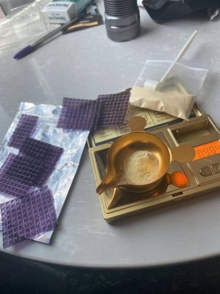 Full sheet of purple pyramid buy LSD gel tabs infused with sparkling gold flakes laid out on a clean surface