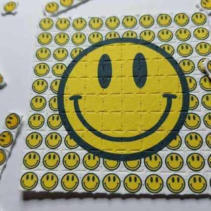 Grid of perforated cotton buy LSD blotter paper tabs printed with vibrant visionary artwork on a clean laboratory surface
